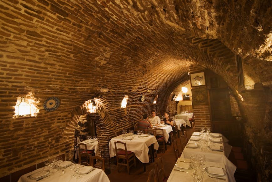 People dining in the curved stone interior of El Sobrino de Botín, the oldest restaurant in the world, in Madrid