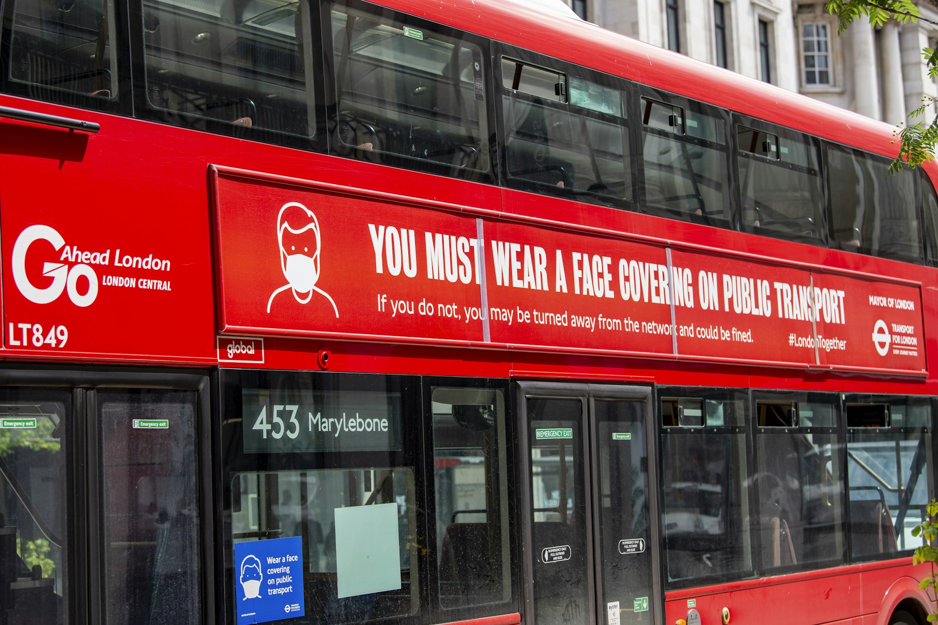 A London bus is seen with a sign reading 'you must wear a face mask'
