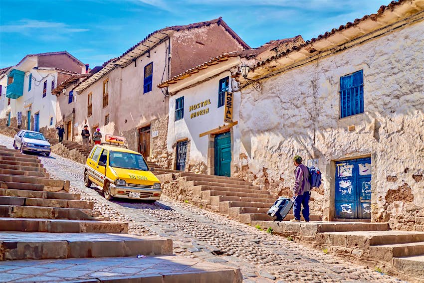 A taxi walks down a steep cobbled street in the historic center of Cusco.  The buildings lining the streets have been turned into quaint hotels.