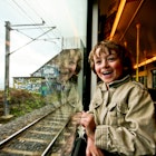 A very excited young boy looks out of a train window.