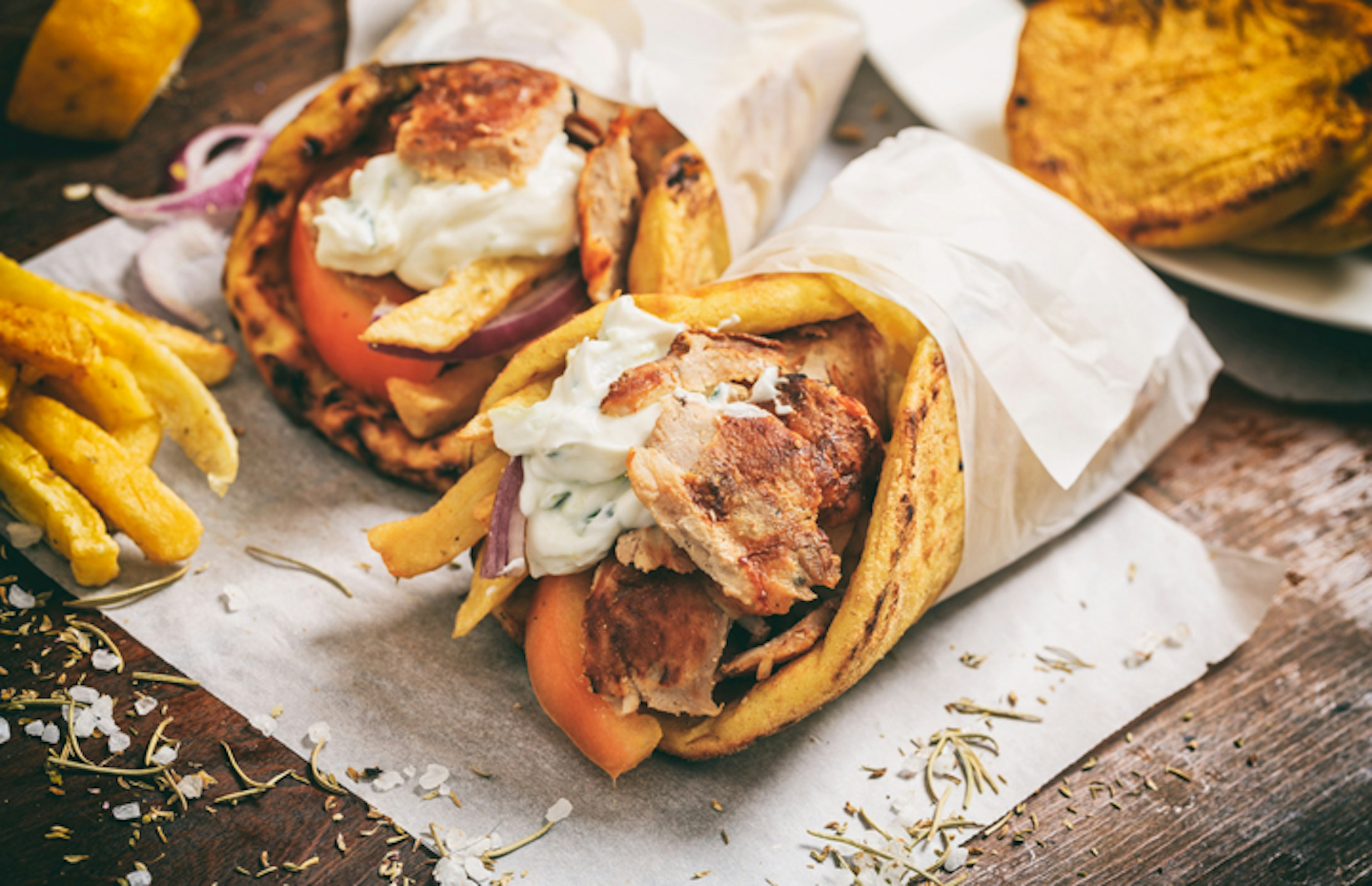 Greek gyros wraped in a pita bread on a wooden background