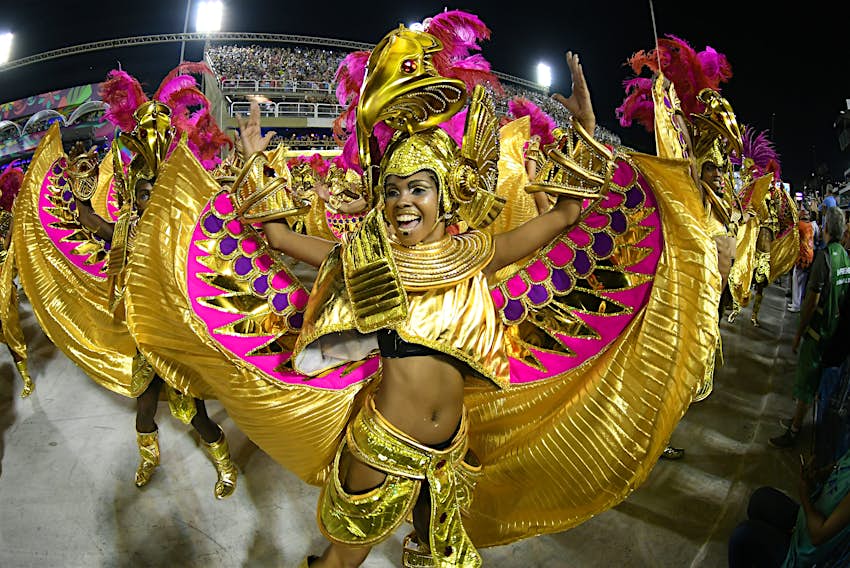 Mulheres dançam em elaborados trajes dourados no desfile das escolas de samba para o grupo especial durante o Carnaval do Rio de Janeiro