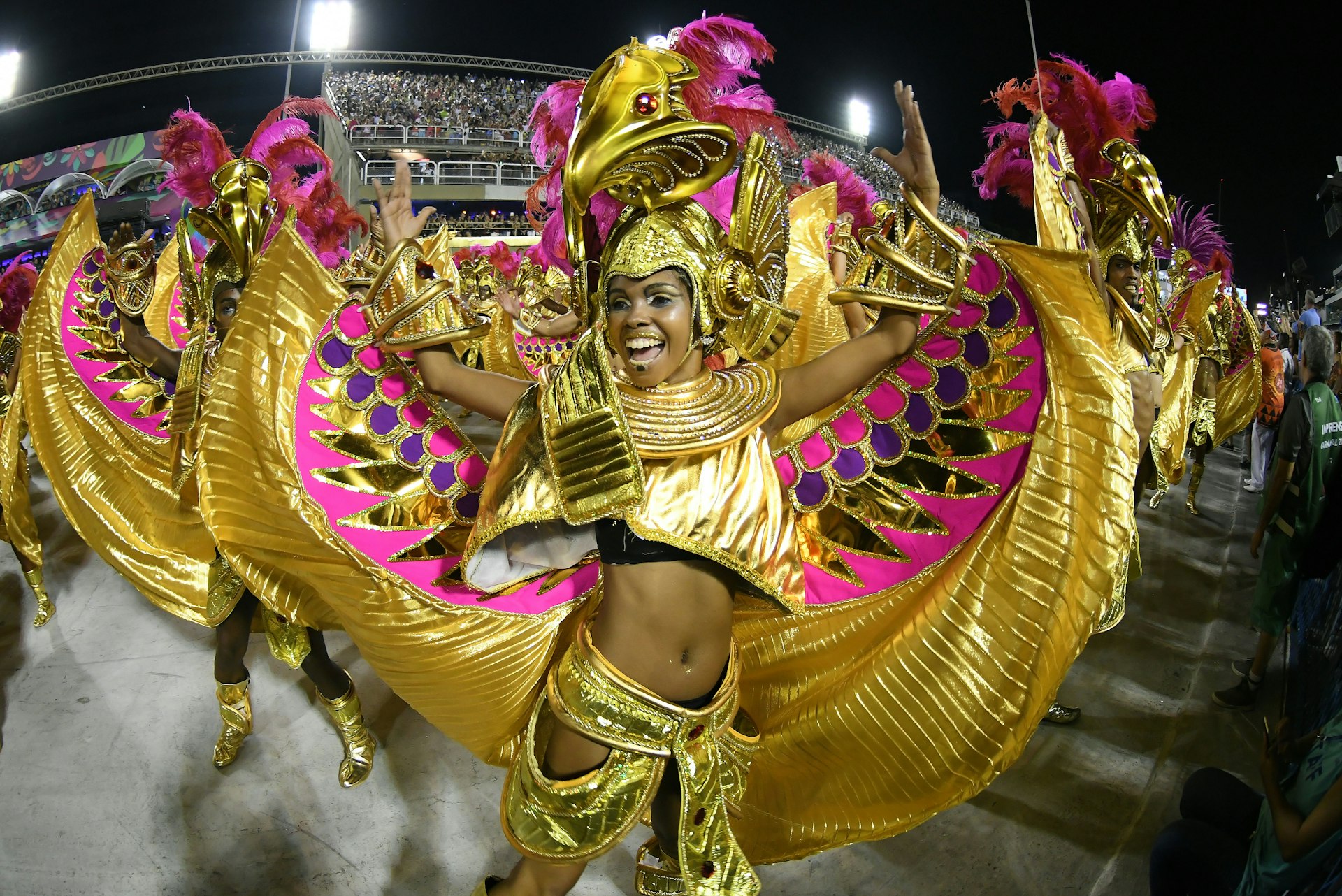 Women dance in elaborate gold costumes at the Parade of the Samba Schools of the Special Group during the Carnival of Rio de Janeiro