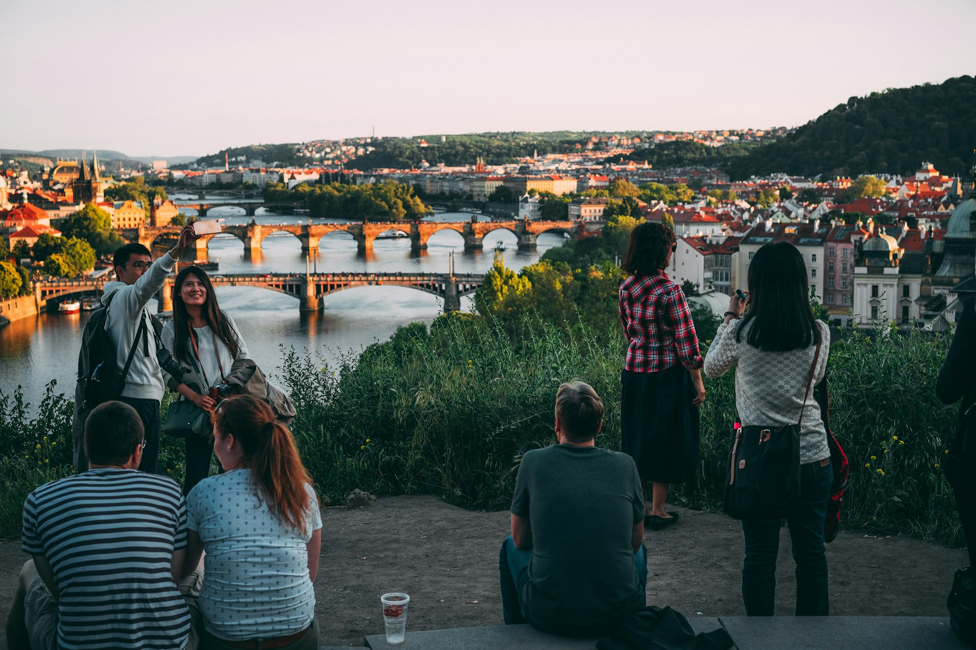 People enjoying the sunset over a city with a river running through the center of it