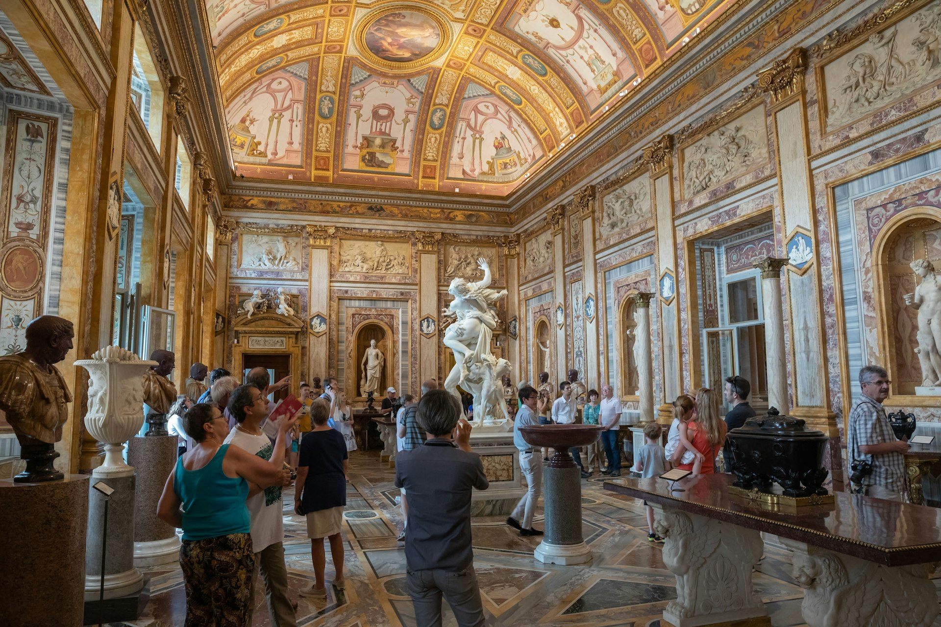 A large room with people admiring art. There's a huge marble sculpture in the center of the room