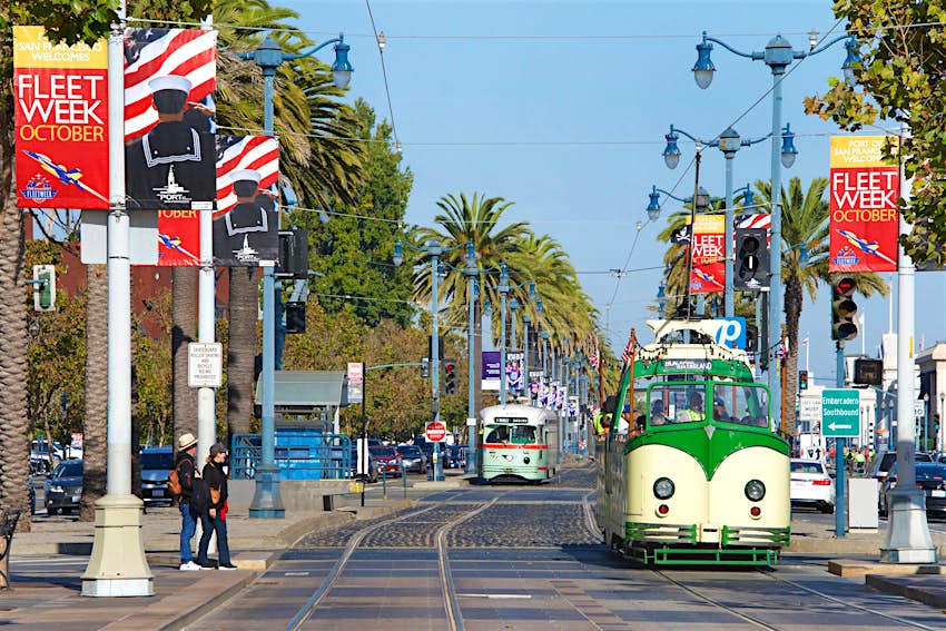 A cream and green F Market & Wharves historic streetcar heads along the straight road leading to Fisherman's Wharf in San Francisco. 