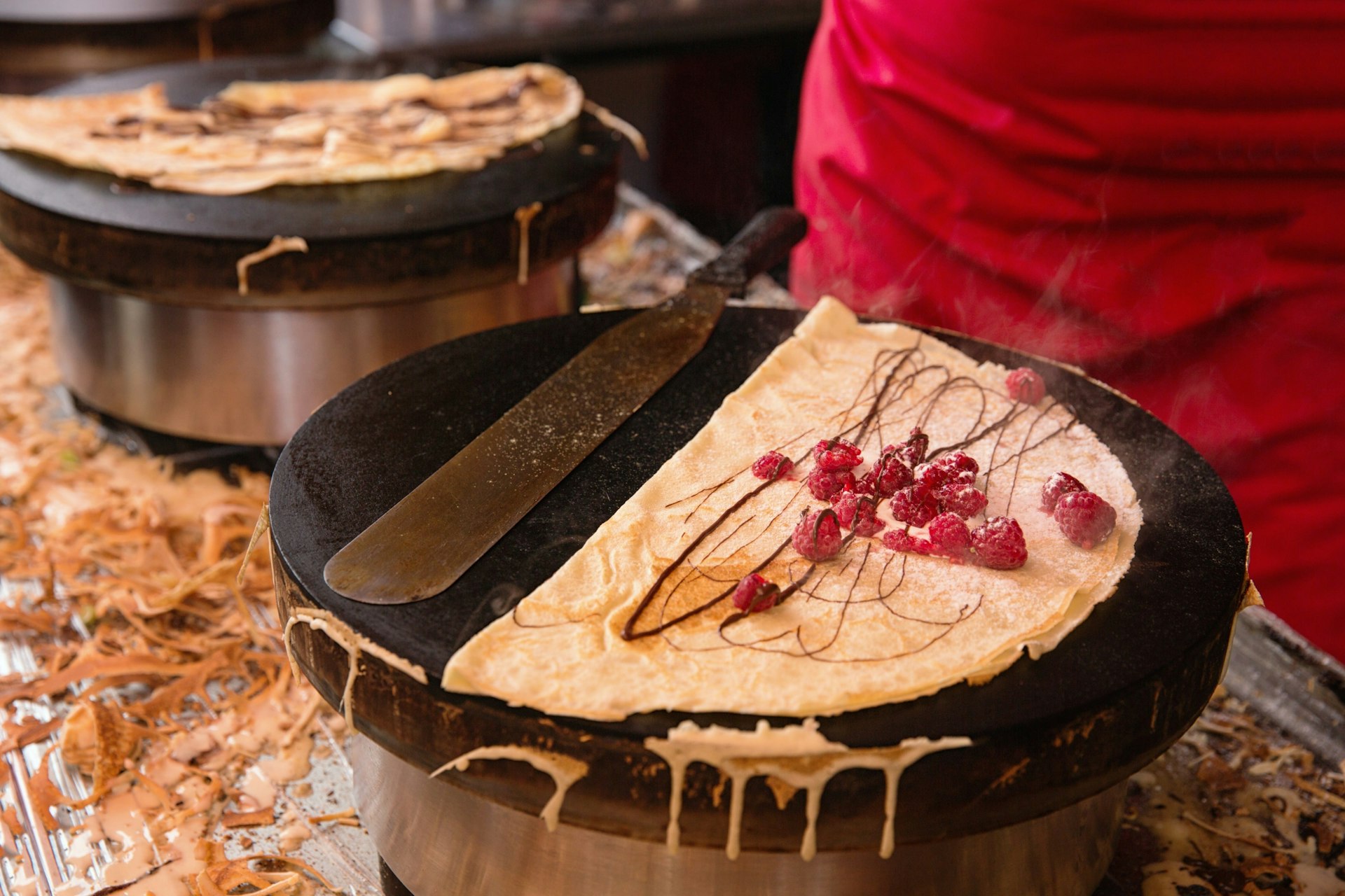 A crepe with raspberries being cooked on a hot plate by a street vendor in Paris, France.