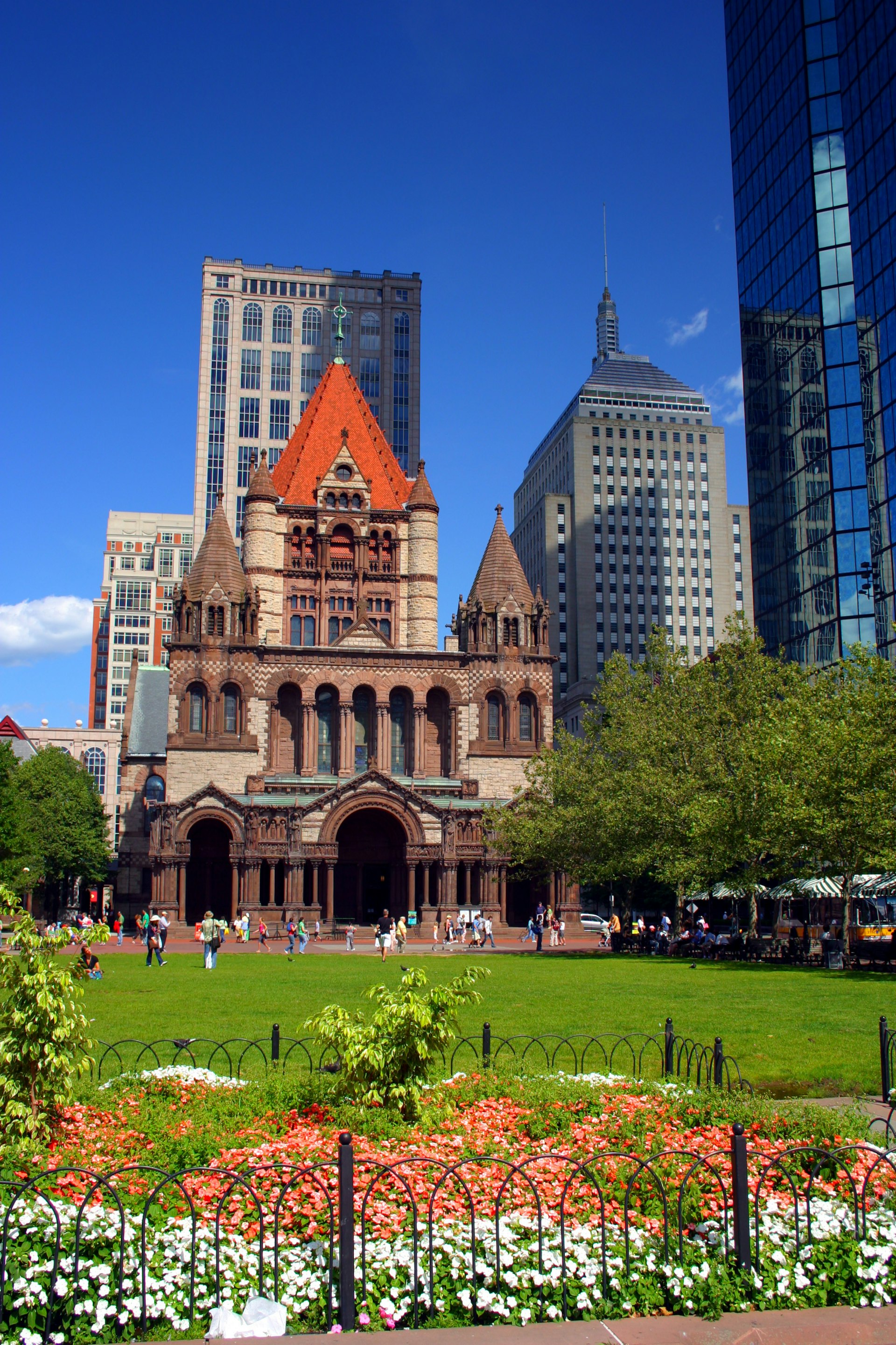 A Romanesque-style church in a large green space surrounded by skyscrapers