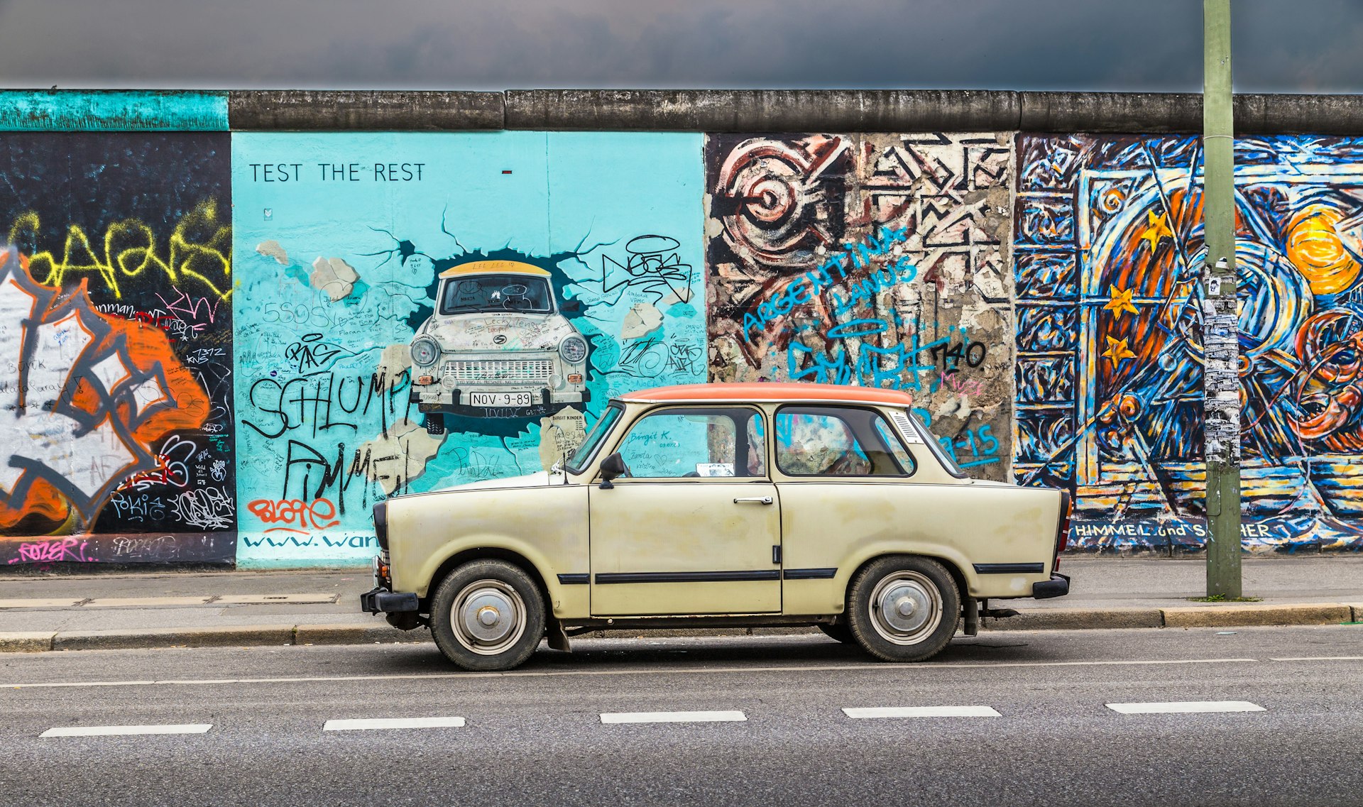 An old Trabant parked in front of the Berlin Wall at the East Side Gallery