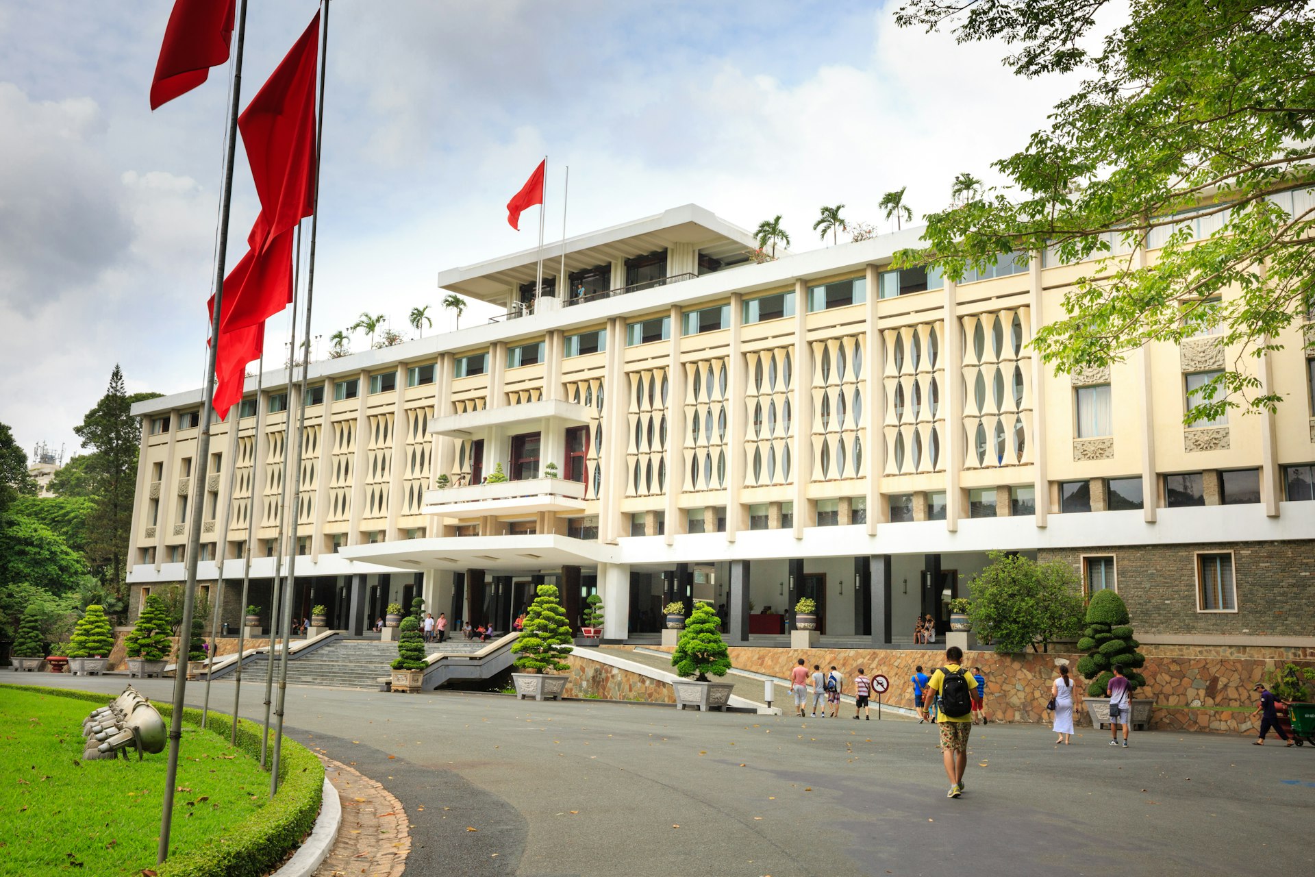 A tourist walks along the path towards the Reunification Palace in Ho Chi Minh City with Vietnamese flags flapping in the wind