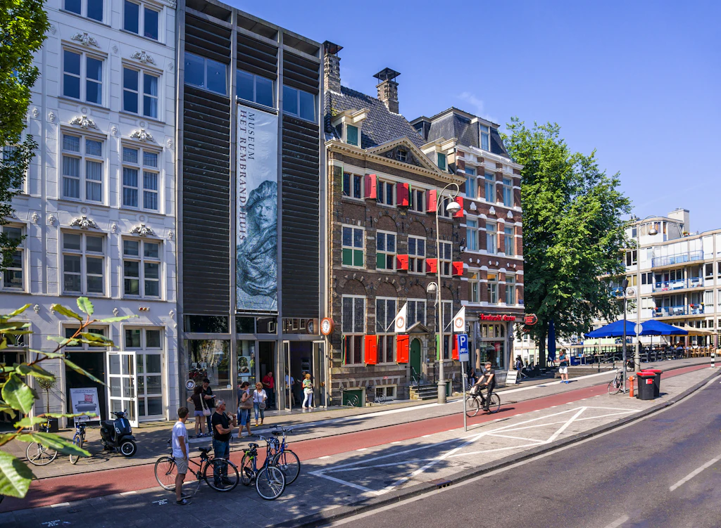 The exterior of the Museum het Rembrandthuis in Amsterdam on a sunny day with people mingling outside