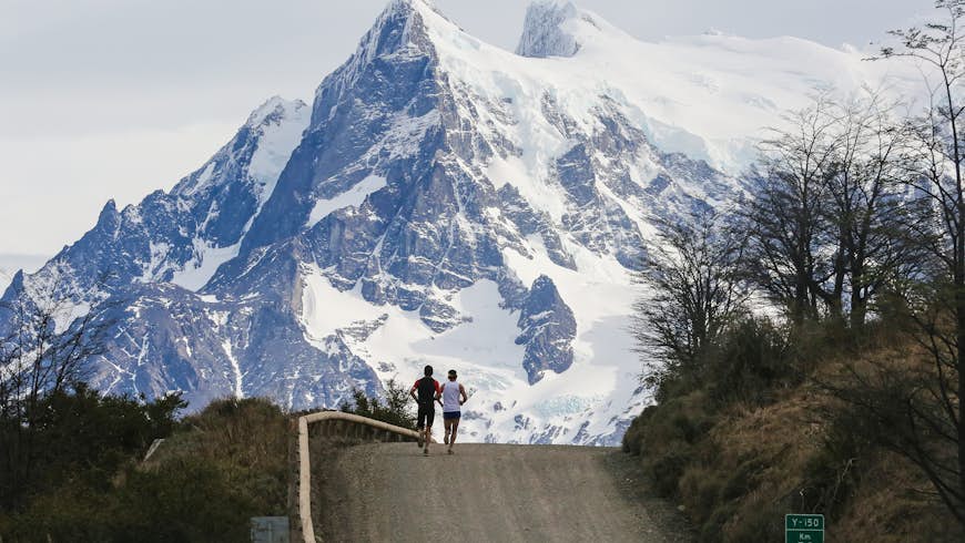 Los atletas que compiten durante el Maratón Internacional de la Patagonia corren por encima de la carretera, contra un fondo de montañas cubiertas de nieve.