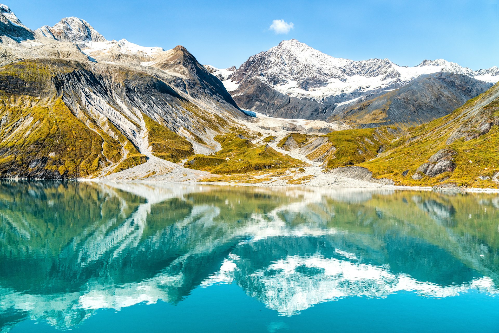 Amazing glacial landscape showing mountain peaks and glaciers on clear blue sky summer day. Mirror reflection of mountains in still glacial waters.