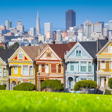 Classic postcard view of famous Painted Ladies, a row of colorful Victorian houses at scenic Alamo Square, with San Francisco skyline in the background on a beautiful sunny day with blue sky in summer