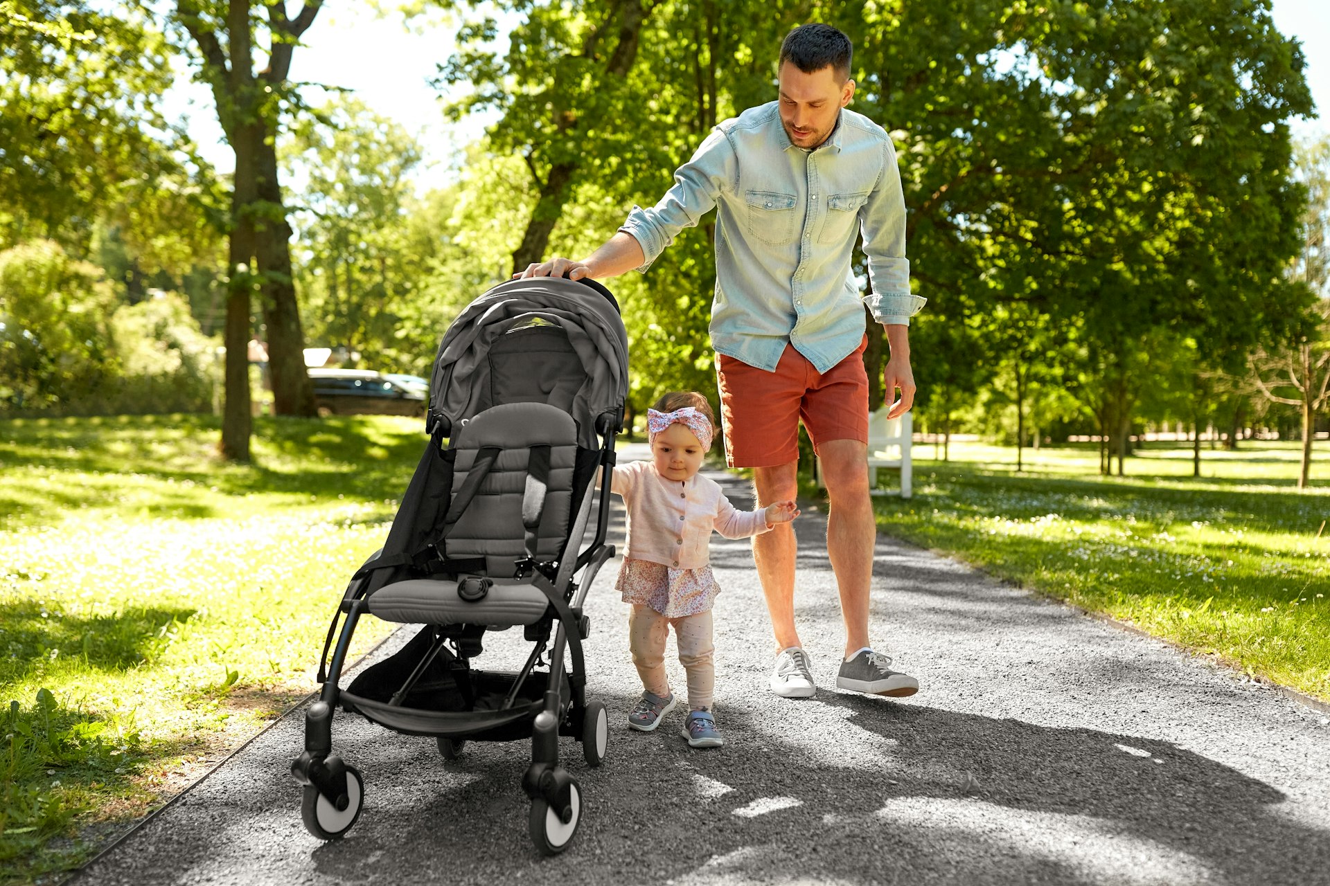 A happy father with child in stroller walking at summer park in Sydney