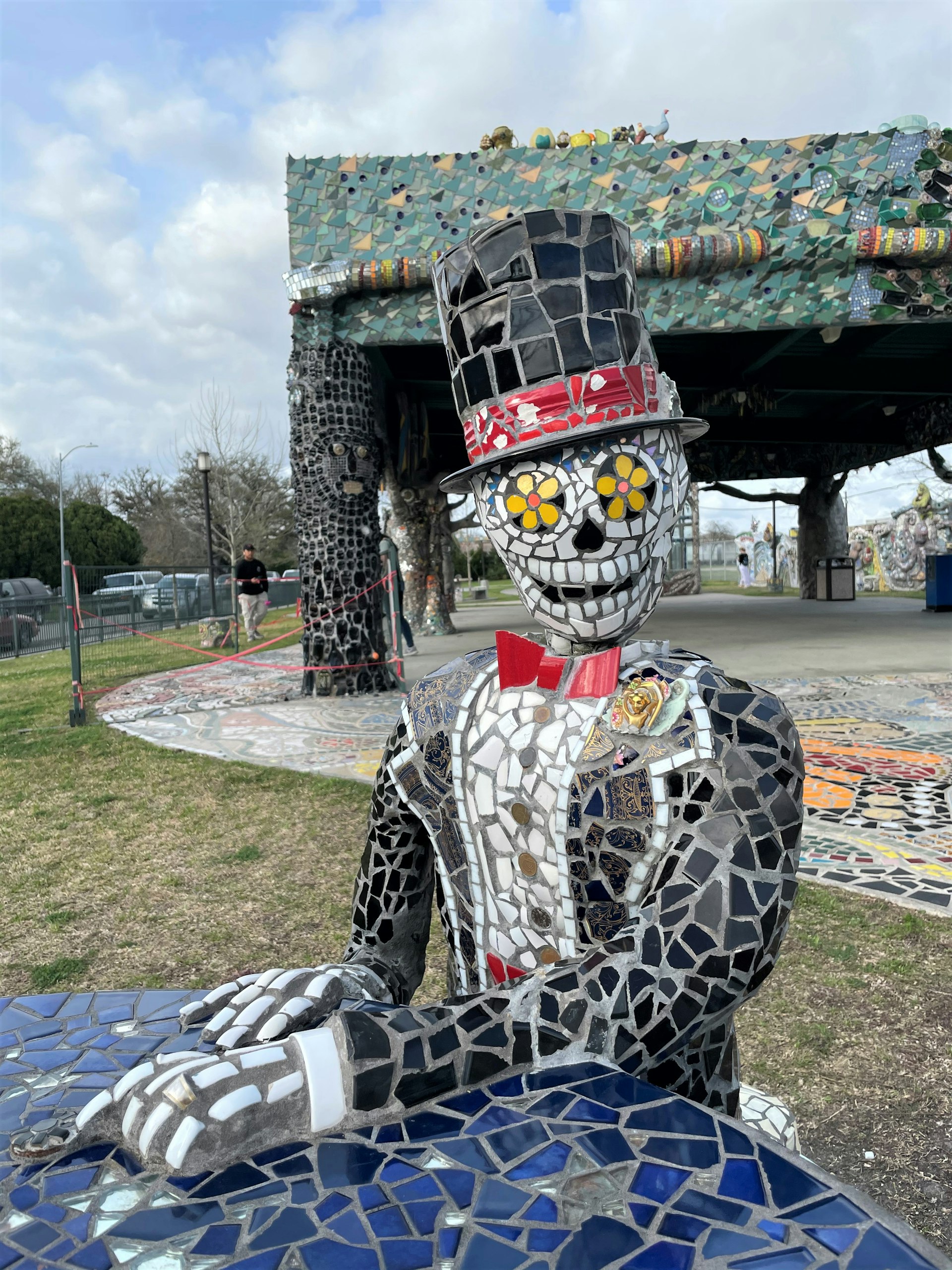 A colorful mosaic sculpture of a skeleton in a tuxedo