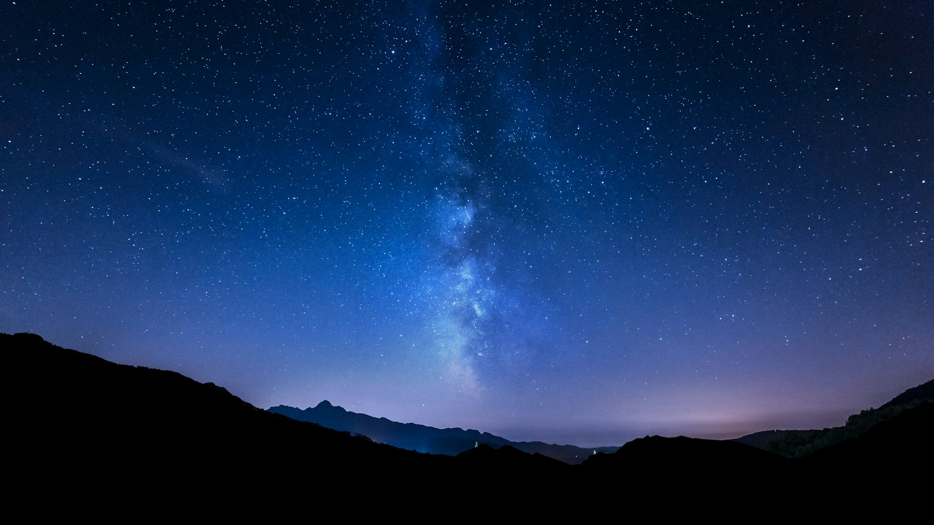 Night sky panorama with stars and Milky Way behind mountain