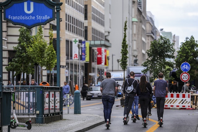 People on E-scooters ride along Friedrichstrasse in Berlin