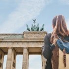 A tourist girl with a backpack or student looking at the Brandenburg Gate in Berlin in Germany.