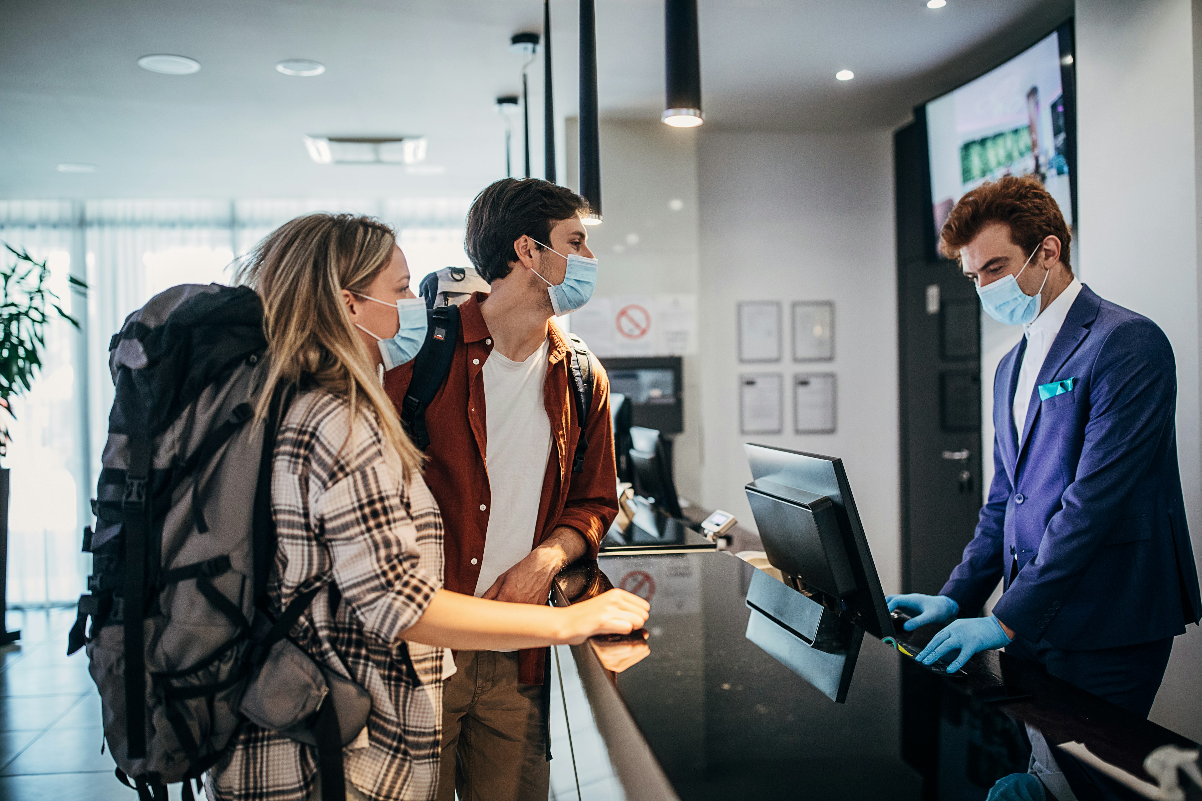 Couple wearing protective face mask while doing check-in at the hotel reception