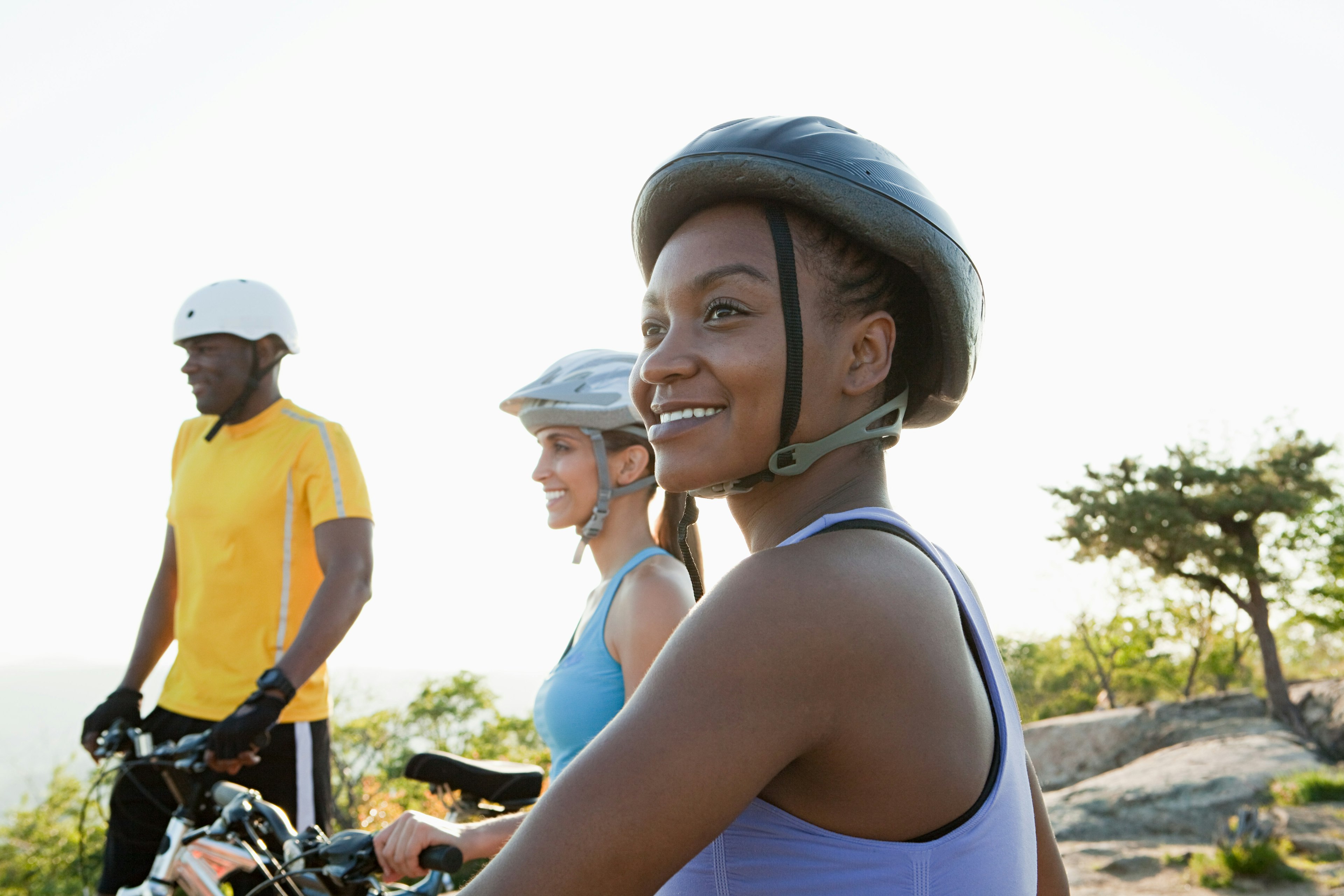 Three cyclists wearing helmets in a rural setting