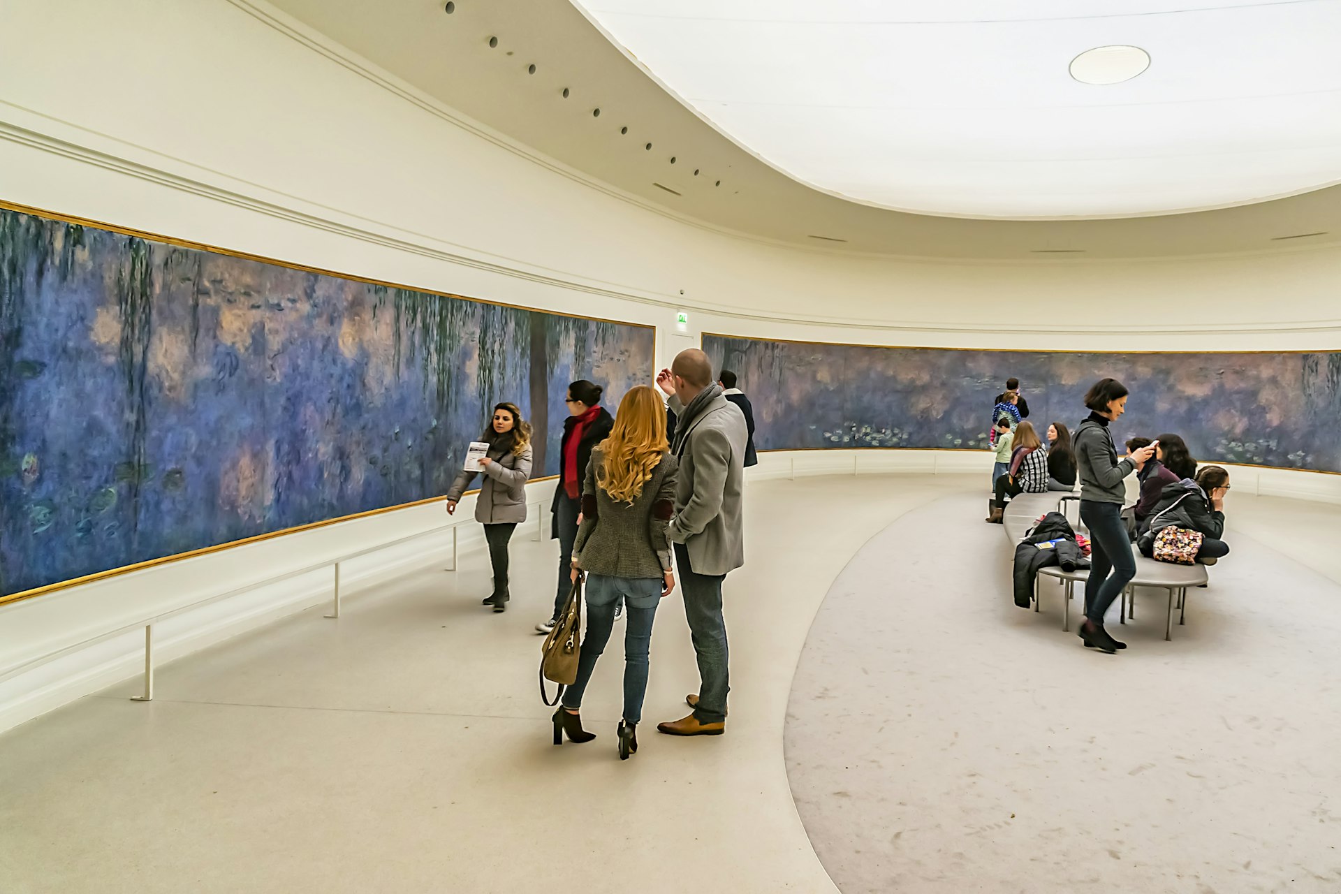 People gathered in an art gallery admiring watercolours on the walls