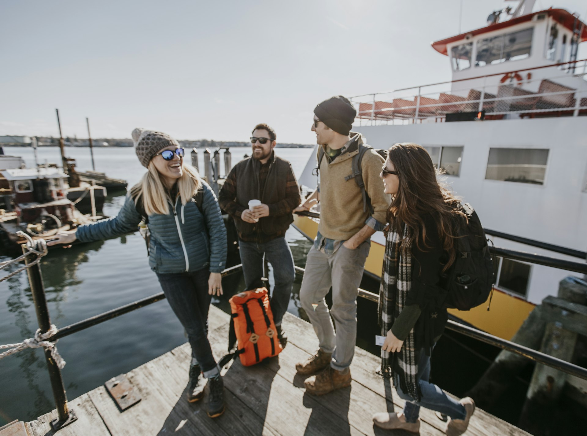 Four young adult friends wait on the waterfront in Portland, Maine