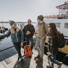 Four young adult friends wait on the waterfront in Portland, Maine
