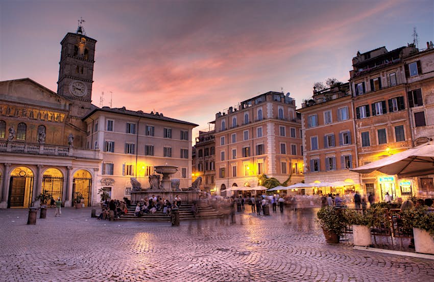 Cafe tables in a Roman piazza at dusk as the sun sets