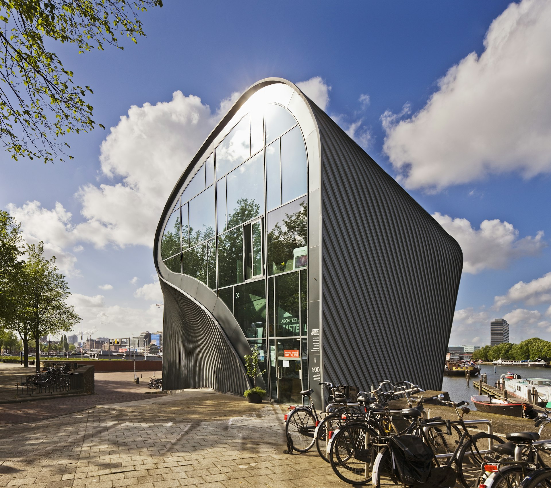 A contemporary curved glass-and-steel building on the edge of a dock