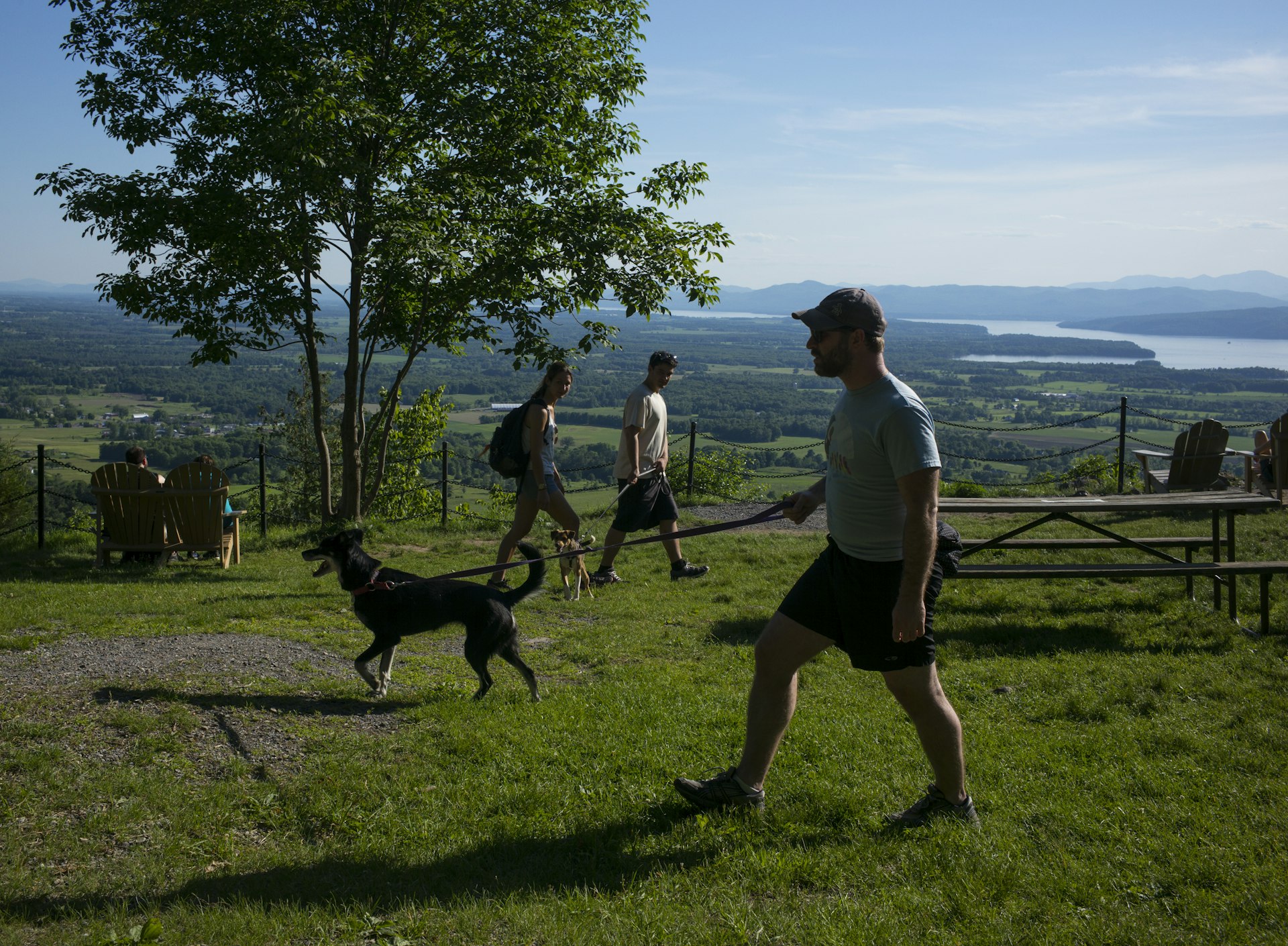 View of hikers, several with pet dogs, at a scenic overlook site in Mount Philo State Park, Charlotte, Vermont. Lake Champlain is visible in the background