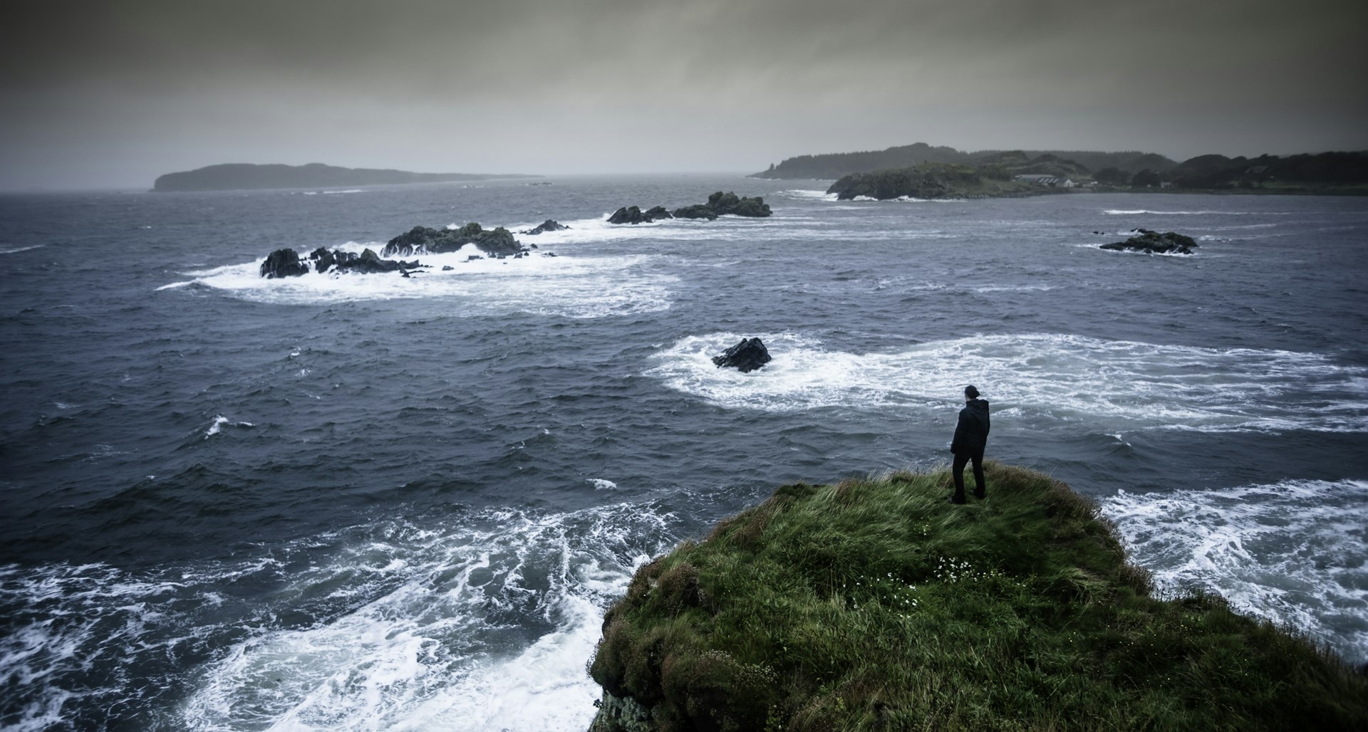 Woman standing on a cliff looking out to sea on the Isle of Islay, Scotland