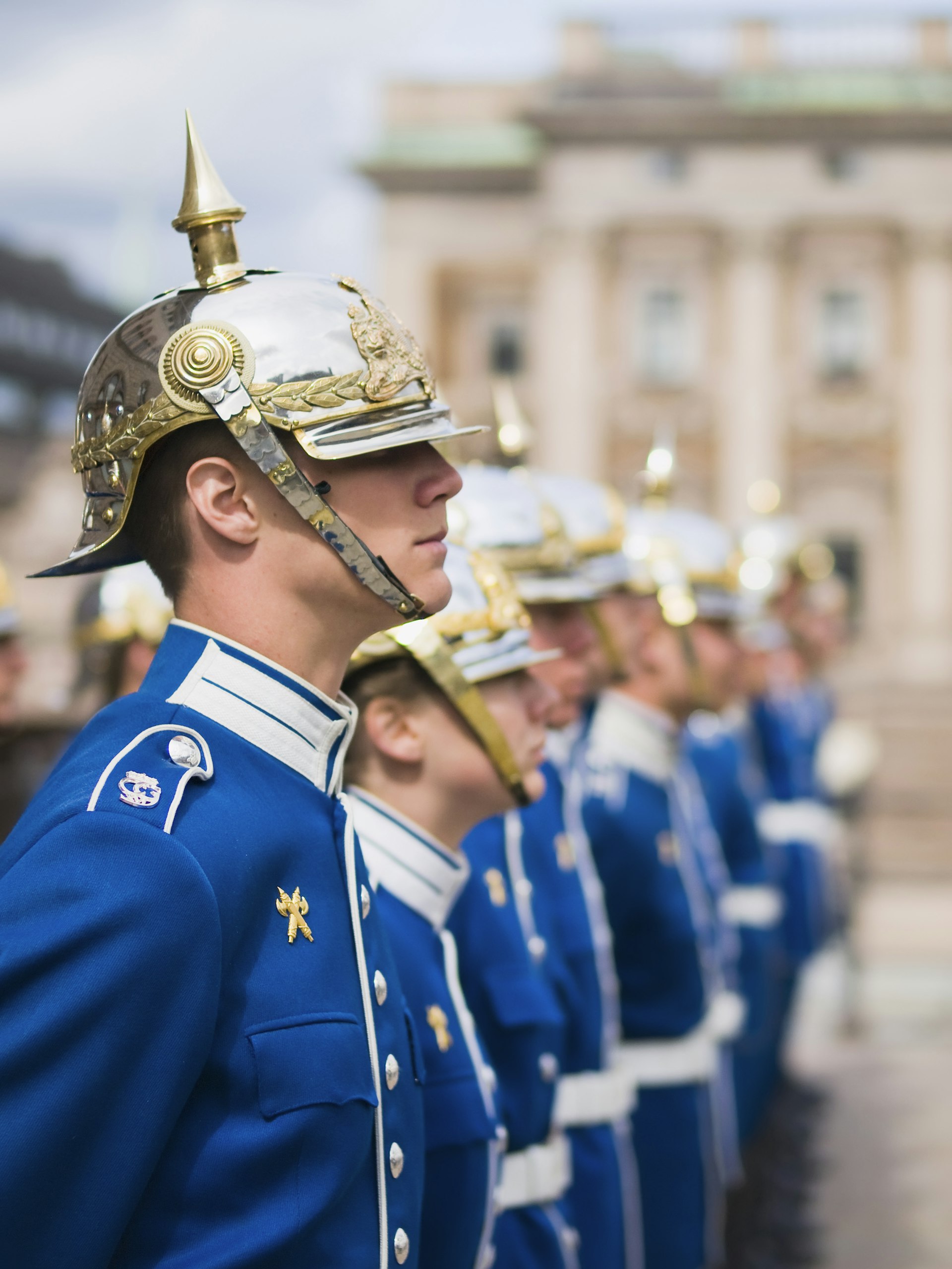 A line of guards wearing blue uniforms trimmed with gold