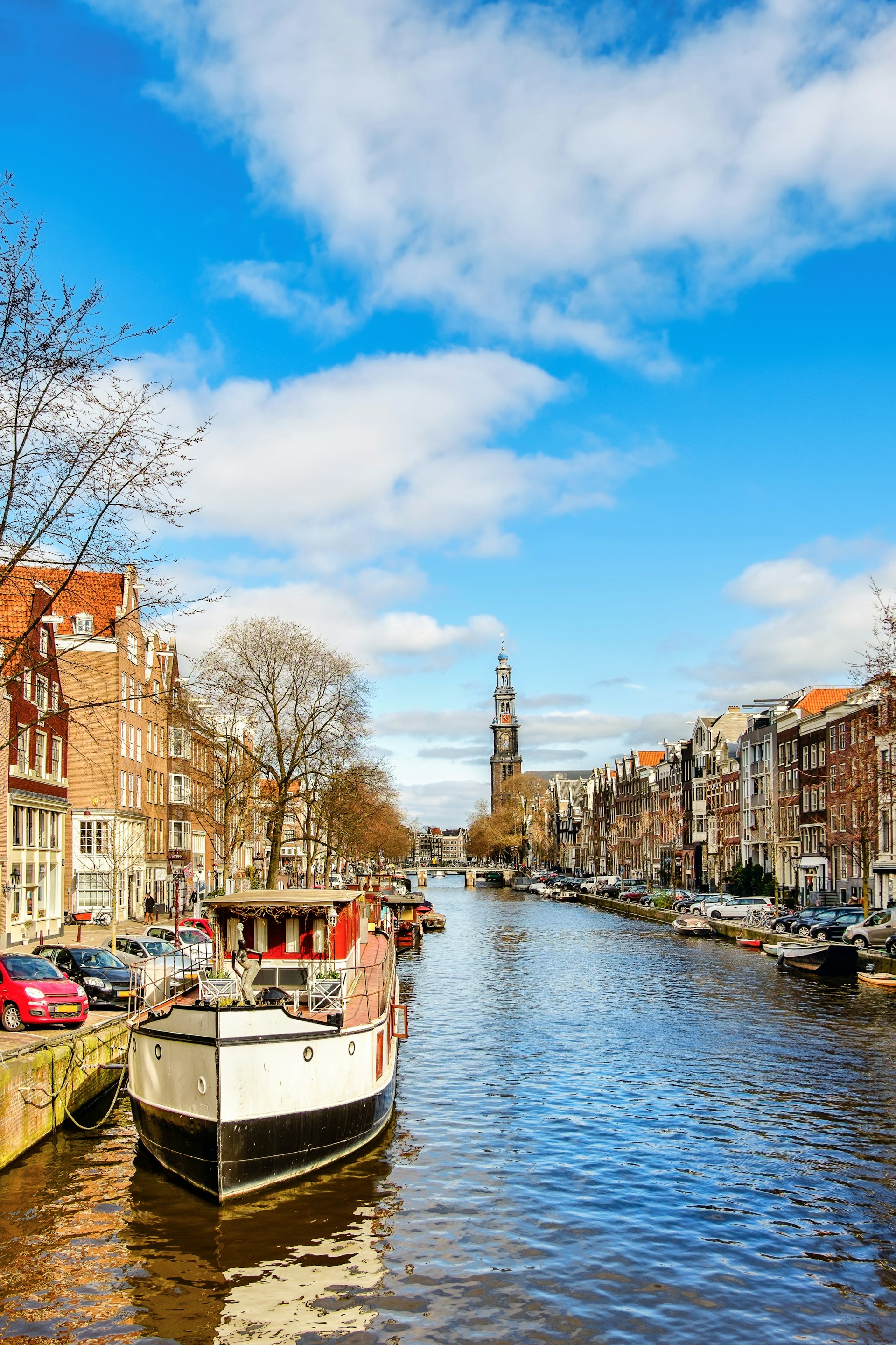 A shot looking along a boat-lined canal towards a church with a tall steeple