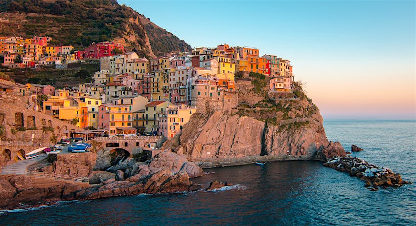 Colorful buildings on a cliffside at sunset in Manarola, Cinque Terre
