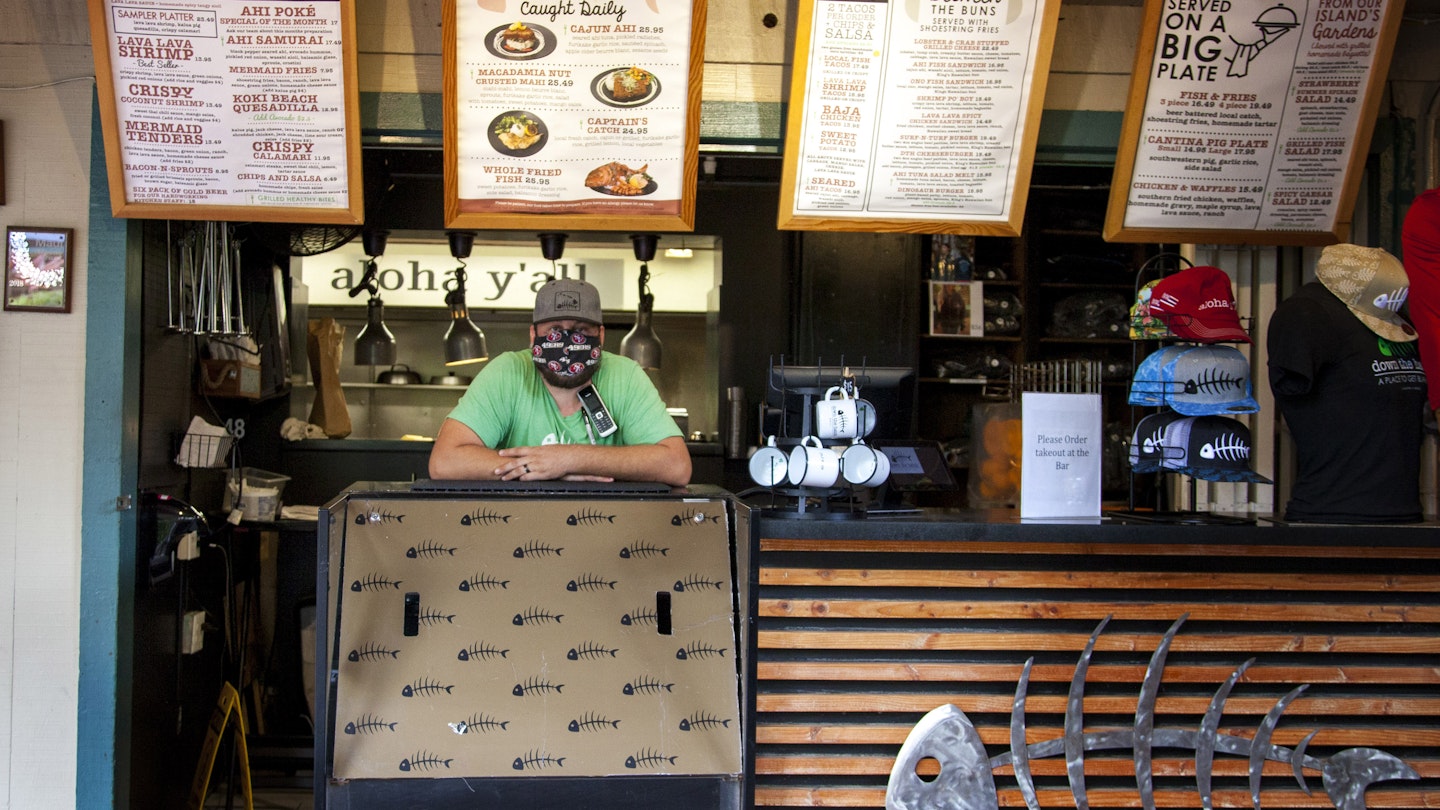 A worker wears a protective mask at Down the Hatch restaurant in Lahaina, Hawaii, U.S., on Friday, April 24, 2020. Tourism makes up one-fifth of Hawaii's economy gross domestic product, with 10 million visitors last year -- that's all but vanished now. In the week ended April 11, spending by visitors dropped 96% compared with last year. Photographer: Mia Shimabuku/Bloomberg via Getty Images