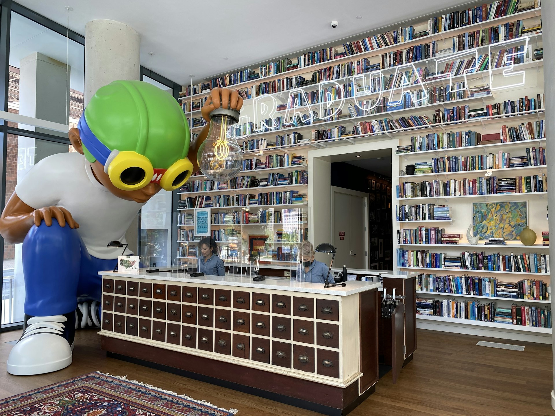 A hotel lobby with an art installation and books on the wall