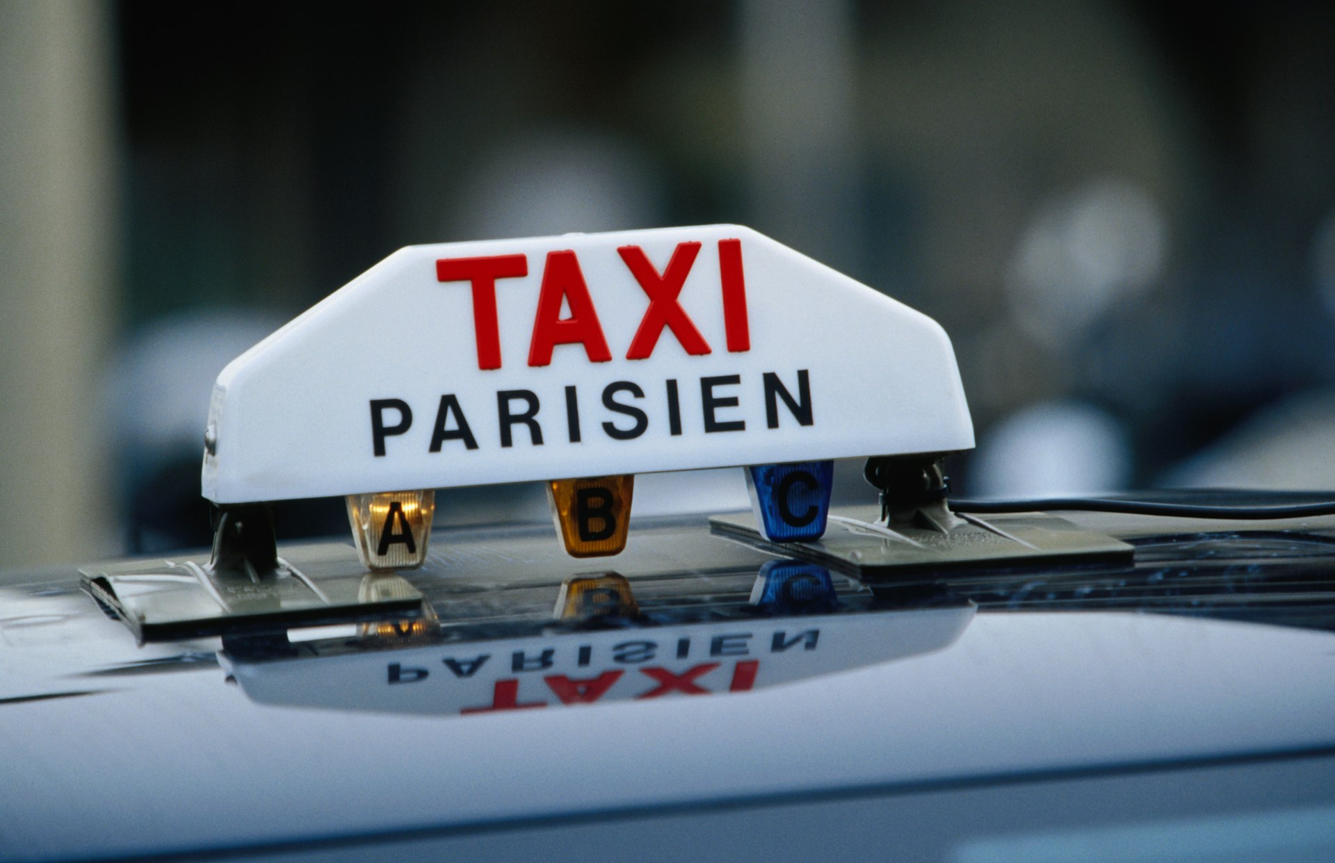 A red-and-white taxi sign on top of a vehicle