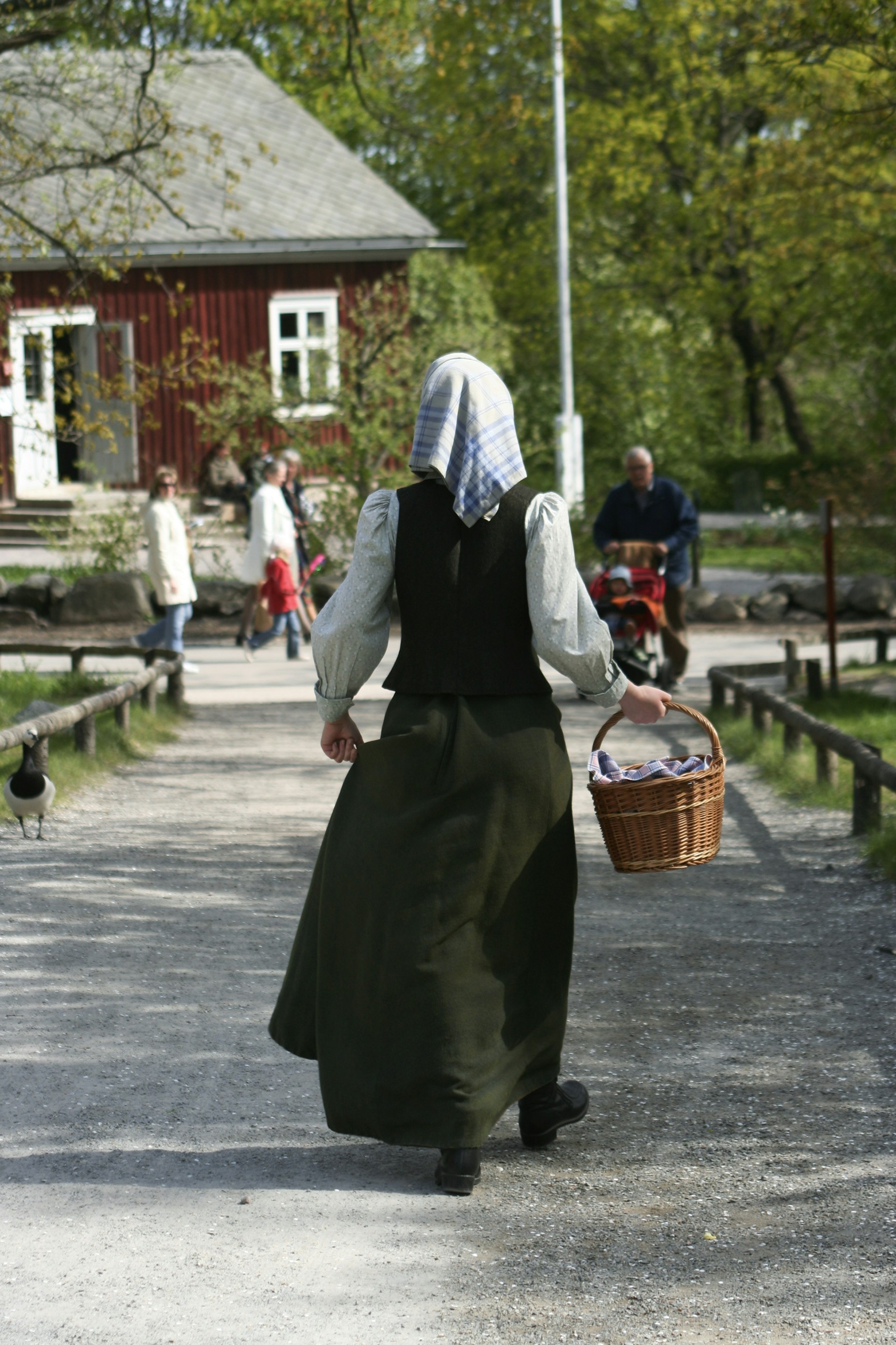 A woman with her back to the camera in period costume at Skansen