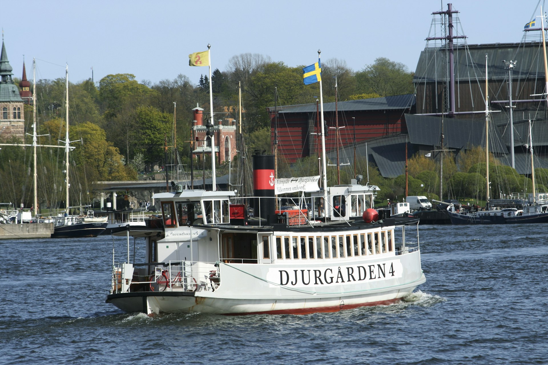 A small white ferry on the water with Djurgarden written on the side 