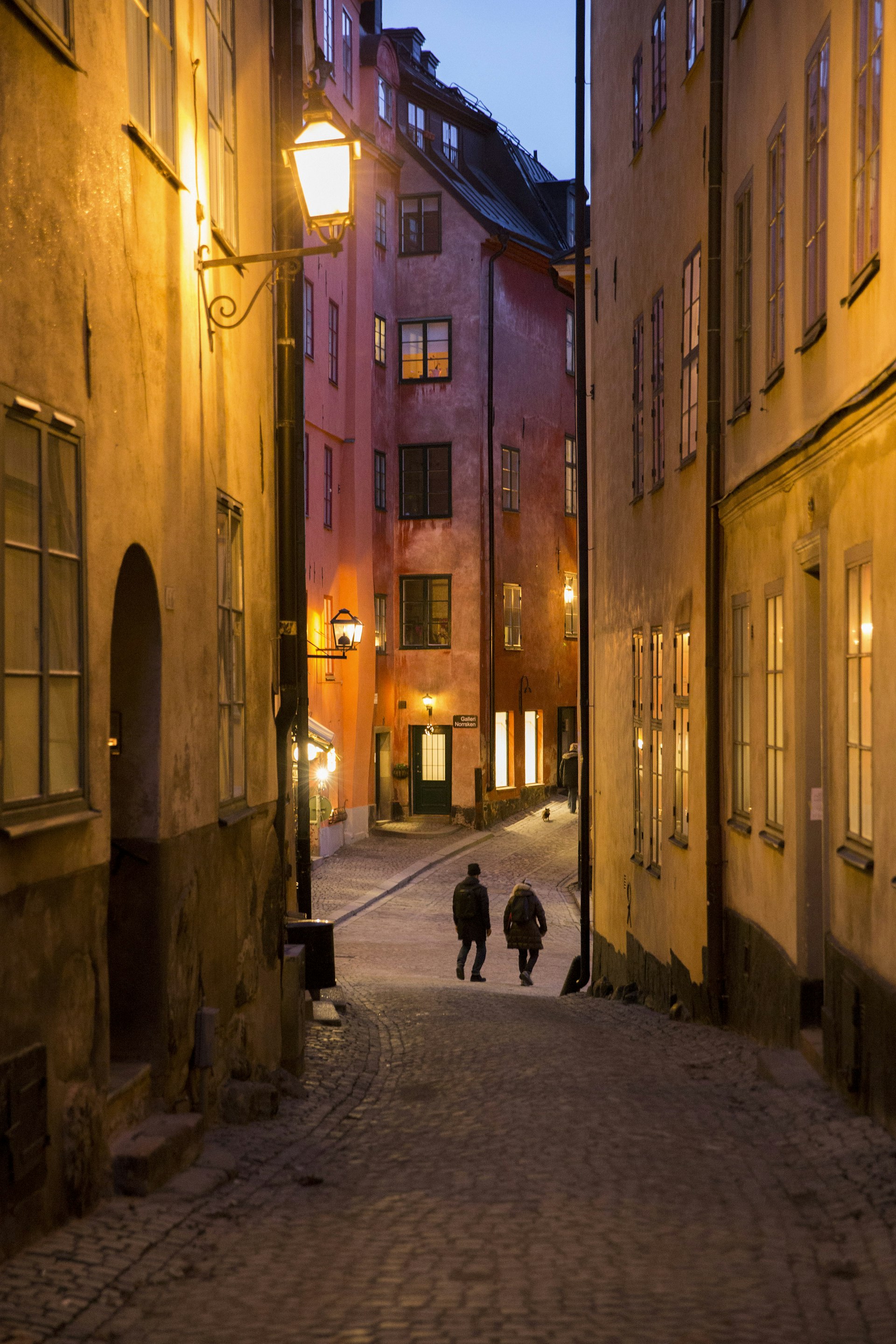 Lamps light up the alleys leading to Kopmantorget (Merchants Square) in Gamla Stan at dusk.