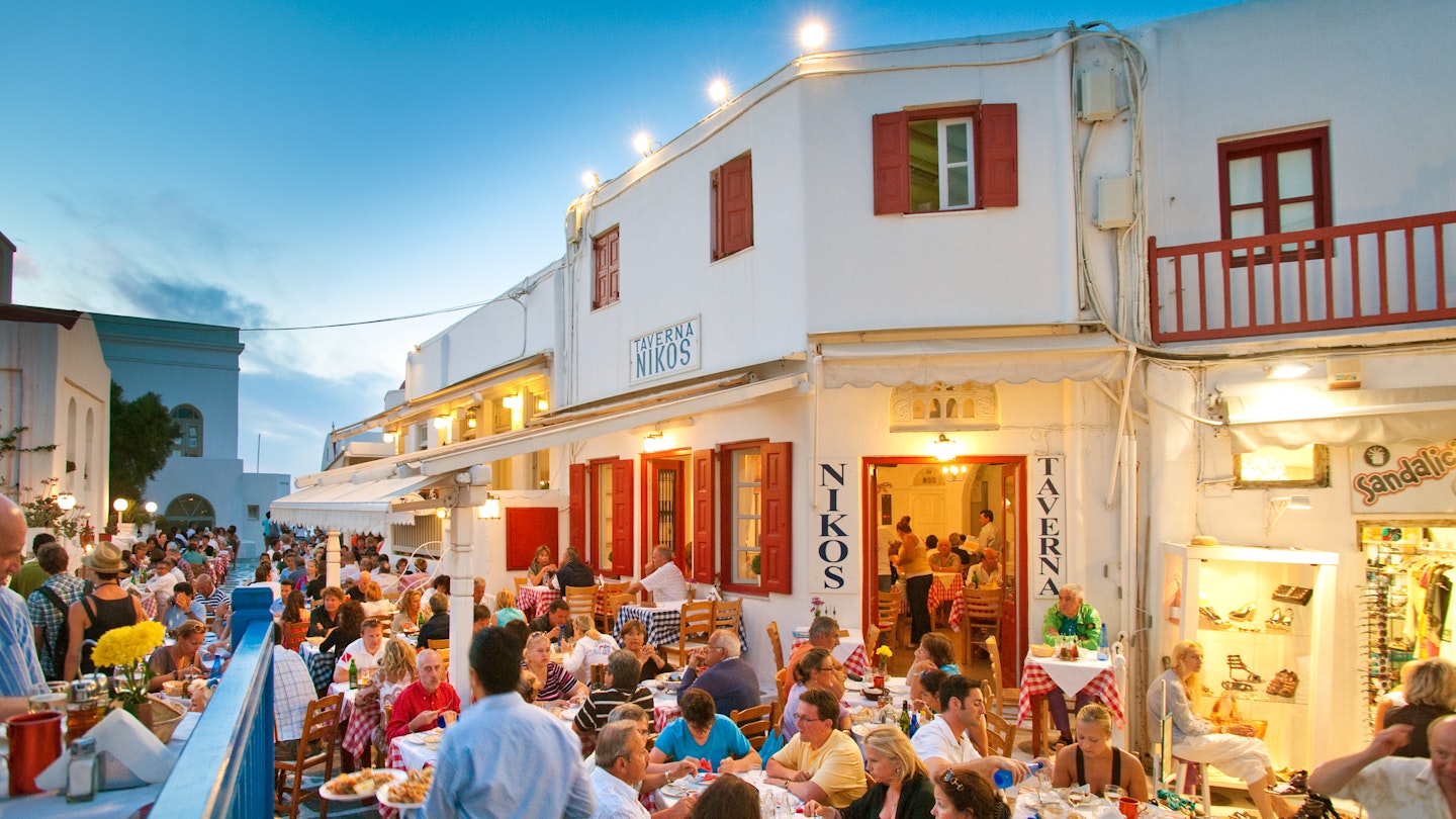 Tourists dining al fresco at Taverna Nikos, in Mykonos, Greece for evening meal.