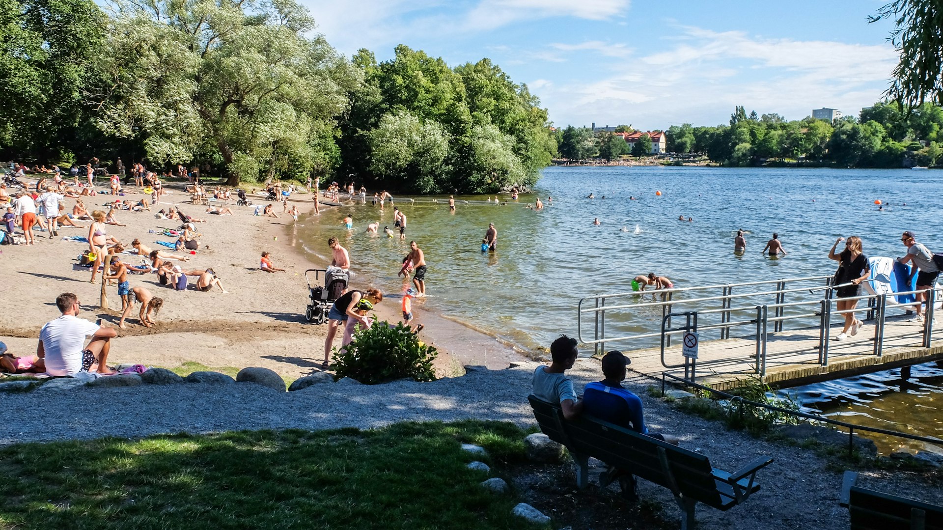 Busy Smedsuddsbadet beach with people relaxing in the summer sunshine
