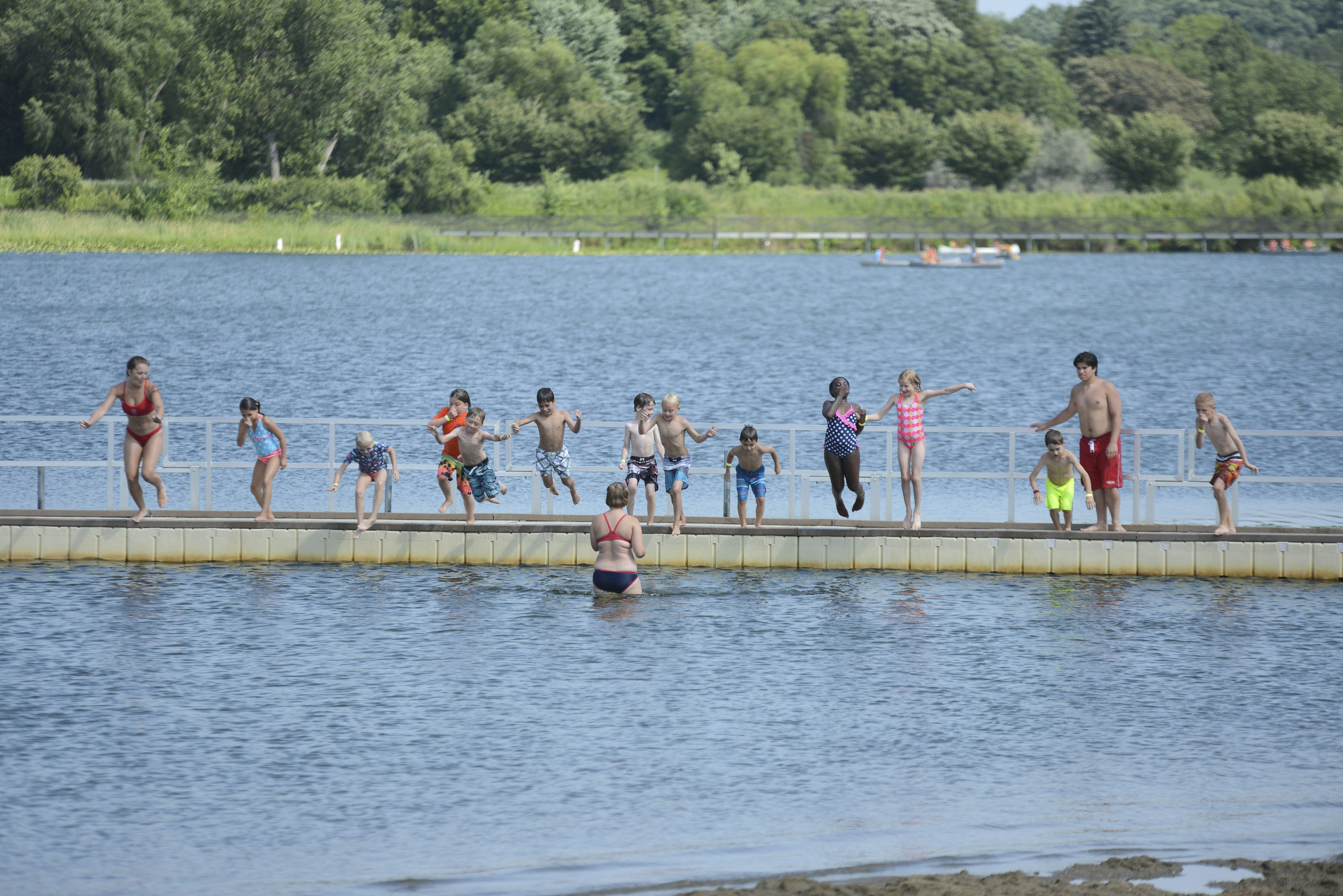 Kids jumping off a dock at Wirth Lake Beach in Minneapolis, Minnesota