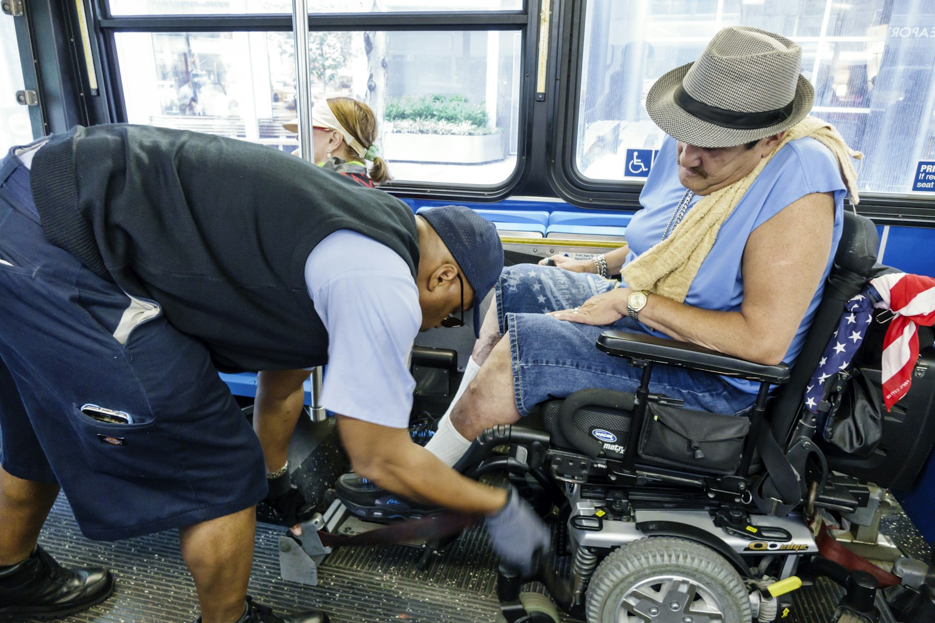 A driver helping a man in an electric wheelchair on a bus in Lower Manhattan.