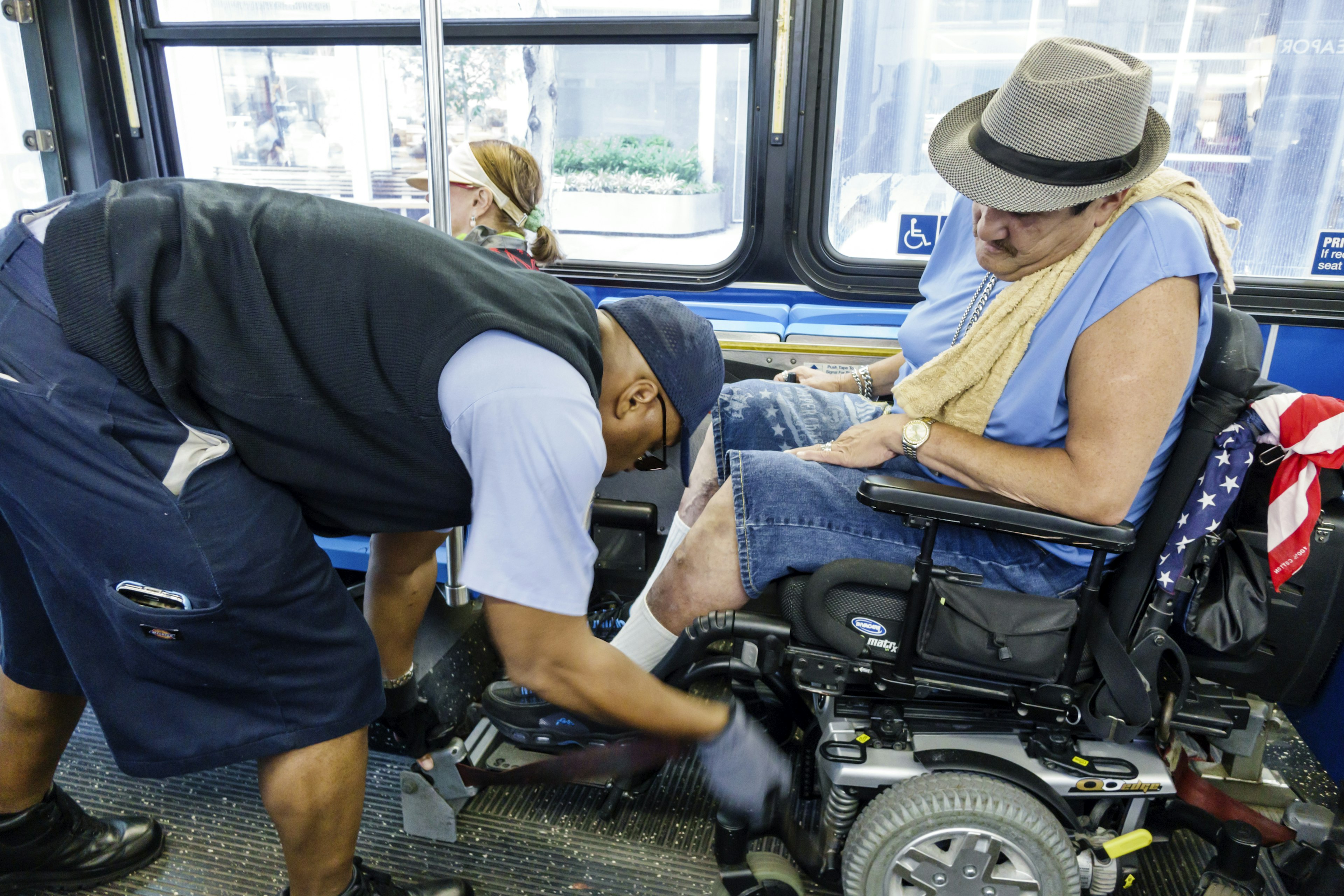 A driver helping secure an electric wheelchair on a bus