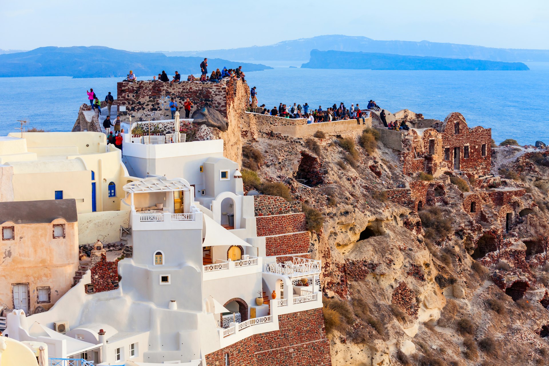 Tourists explore the Byzantine castle ruins on top of a hill in Santorini