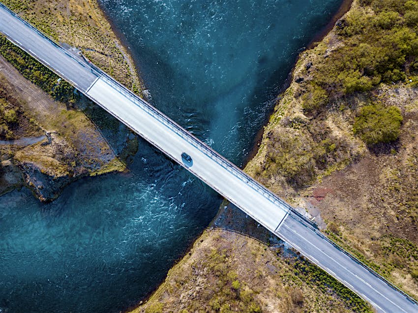 驾驶在有新的大海的桥梁的汽车的空中射击跑在下面。鲑鱼河在冰岛南部的格里姆斯斯山上可以看出。