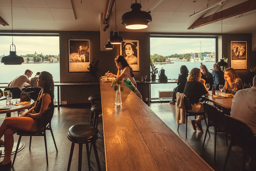 Fotografiska cultural center, Stockholm Groups of people sitting at tables in the restaurant at Fotografiska with views over the water.