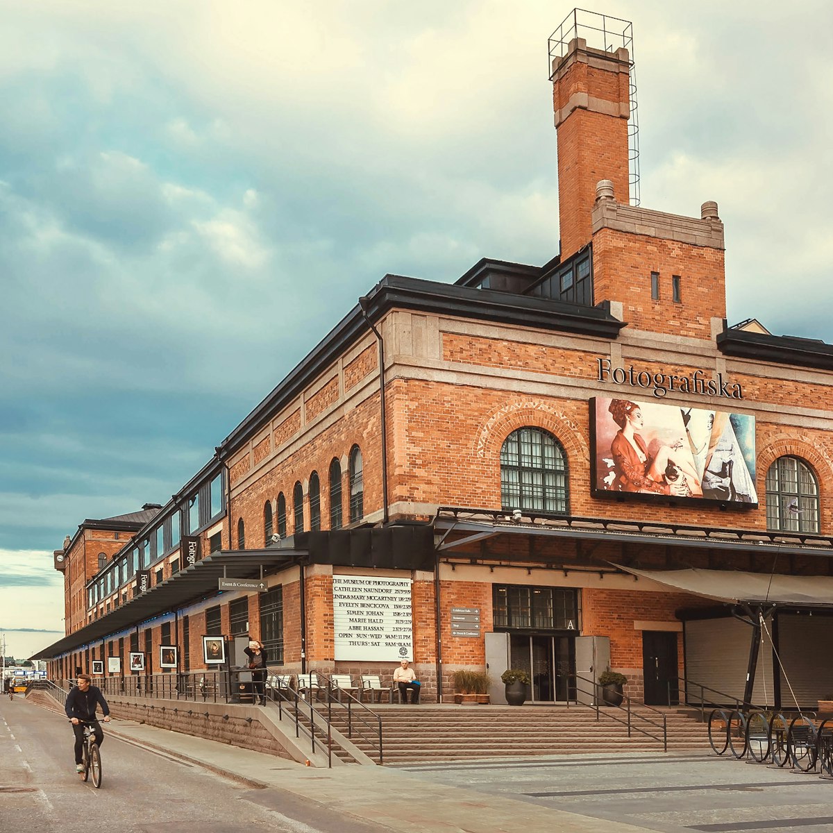 A local cycles past the exposed brick building housing the Fotografiska in Stockholm